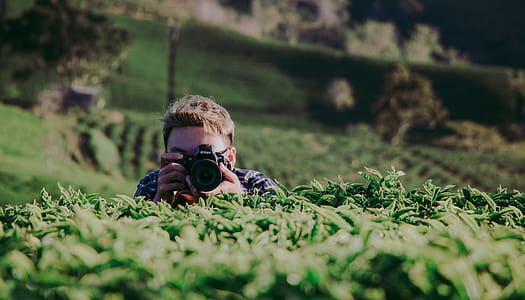 Shallow Focus Photography of Man Holding Dslr Camera thumbnail
