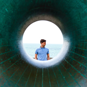 man in blue polo shirt standing distance with ocean during daytime thumbnail