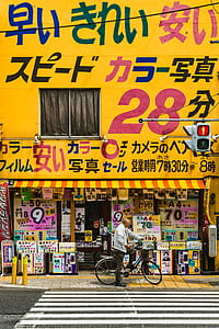 man riding bicycle posting in front of yellow building thumbnail
