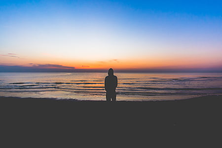 silhouette of man standing on seashore during sunset thumbnail