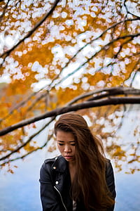 woman wearing black leather jacket near brown trees thumbnail