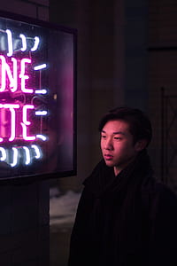 man standing beside neon signage thumbnail