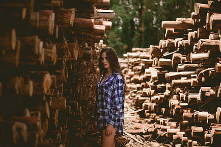 woman standing near pile of wood logs thumbnail