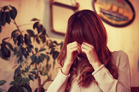 woman wearing brown sweater near green plants thumbnail