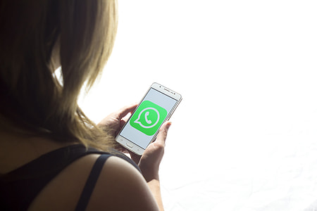 woman holding phone displaying Wattsup application thumbnail