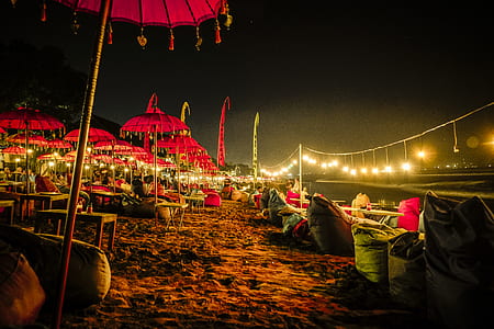 photo of red parasols near garbage bags and body of water photo taken during nighttime thumbnail