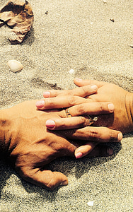 person's hands on white sand thumbnail