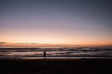 silhouette of man standing on shore during sunset thumbnail