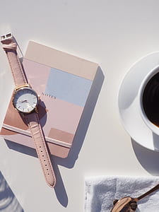 person taking photo of round white analog watch on notes box thumbnail