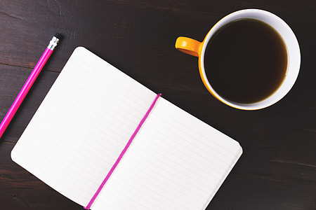 Notepad, notebook, pencil and coffee cup on wooden office desk thumbnail