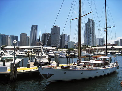 white and brown sailboat docked beside brown wooden platform thumbnail
