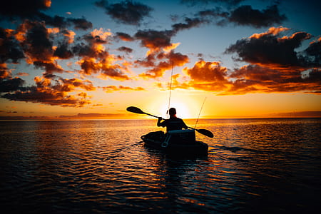 silhouette photography of man riding on boat during golden hour thumbnail