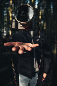 black DSLR camera floating on air above person's hand thumbnail