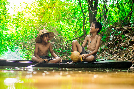 two boys on canoe smiling on rive r thumbnail