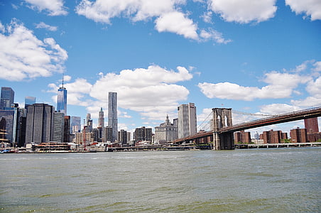 bridge over body of water and high-rise building under blue sky thumbnail