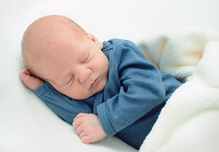 baby wearing dark-blue long-sleeved shirt sleeping on white textile thumbnail