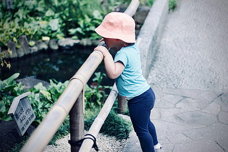 toddler holding fence loking downward thumbnail