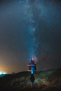 girl standing near lighthouse during night time thumbnail