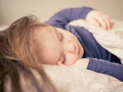 female child wearing blue long-sleeve shirt sleeping in bed thumbnail