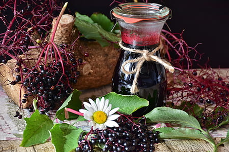 black and red fruit near glass bottle on top of brown wooden surface thumbnail