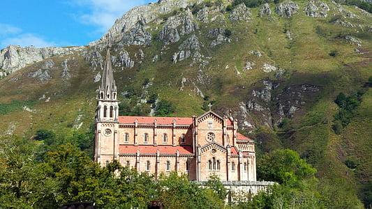 brown and red concrete cathedral surrounded by mountain thumbnail