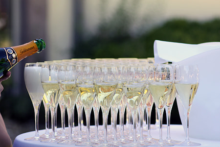 shallow depth of field photo of clear glass champagne flutes filled with liquor on top of table with white cover thumbnail