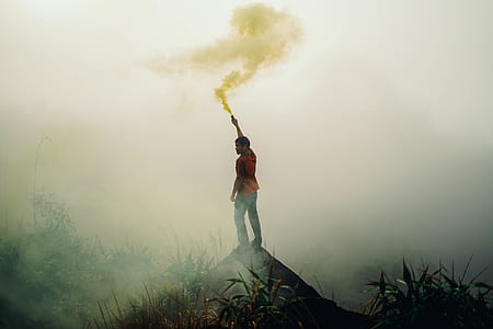 person standing on hill while holding smoke flare thumbnail