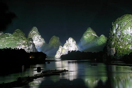 calm body of water with silhouette of island at nighttime thumbnail