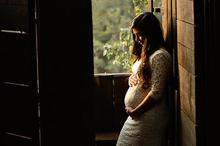pregnant woman leaning on brown wall thumbnail
