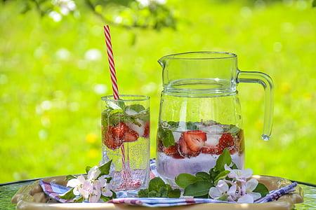half-filled pitcher with slices of strawberries beside filled cup thumbnail