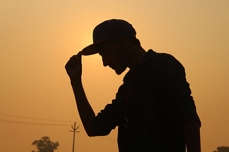 silhouette of man holding his cap during dusk thumbnail