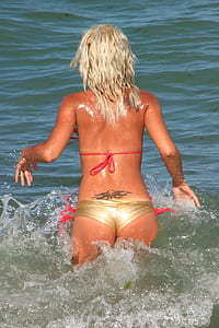 woman wearing red and gold bikini on body of water during daytime thumbnail