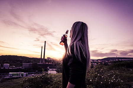 Young Woman Enjoying a Drink in Sunset thumbnail