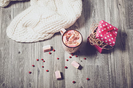 pink glass mug beside knitted textile on brown wooden surface thumbnail