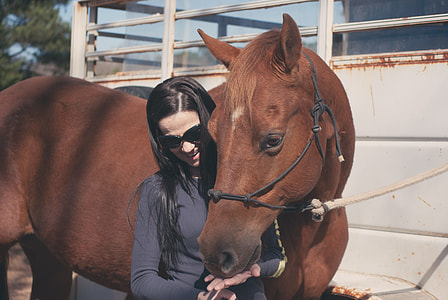 woman in gray sweatshirt touching brown horse during daytime thumbnail