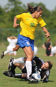 selective focus photo of woman in black laying on ground while catching ball beside woman in yellow shirt thumbnail
