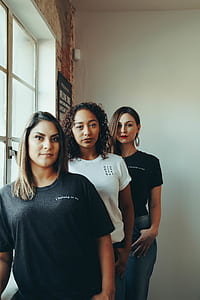 three women standing beside windowpane thumbnail