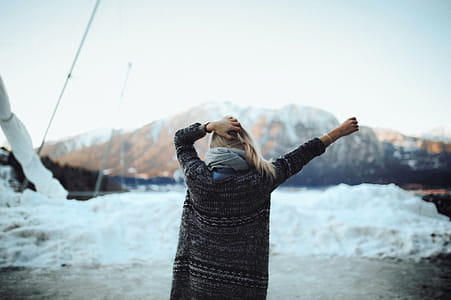 Woman in Gray and Black Tribal Cardigan Standing in Front of Snow Fields thumbnail