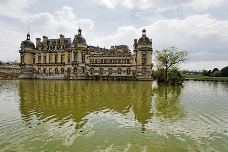 beige and gray concrete castle beside body of water and grass field thumbnail