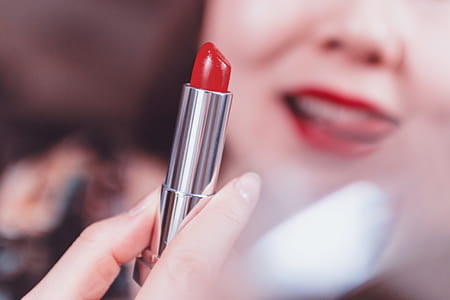 Beautiful woman applying red lipstick thumbnail