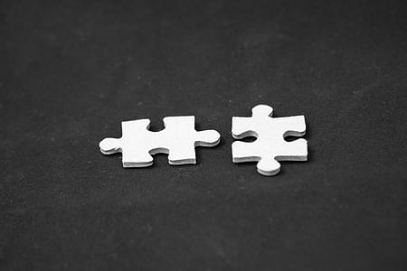 two white jigsaw puzzle pieces on black surface thumbnail