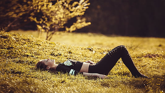 woman in black crop top and black pants lying on green grass during daytime thumbnail