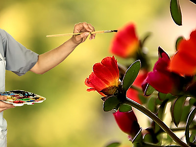 person in grey shirt painting red flowers forced perspective macro photography thumbnail