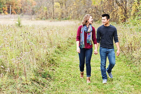 couple walking on green grass pavement in the forest during daytime thumbnail