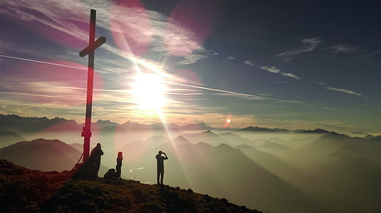 silhouette photo of three person standing beside cross during sunrise thumbnail