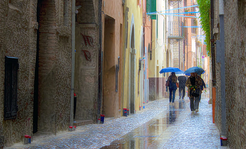person holding umbrellas between houses thumbnail