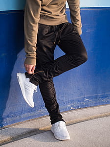 man standing wearing brown jacket, black pants and white running shoes thumbnail