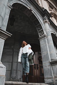 woman standing on gray concrete building near brown wooden door thumbnail