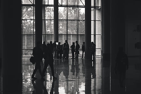 grayscale photography of people walking near concrete columns thumbnail