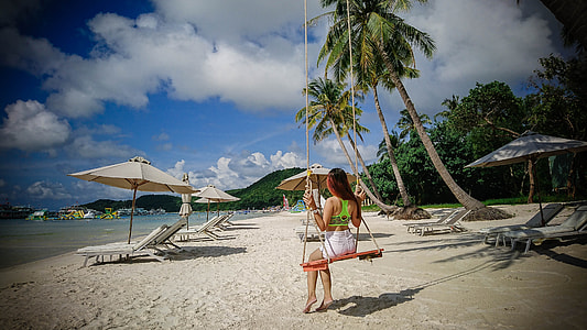 woman sitting on orange swing at seashore under gray clouds thumbnail